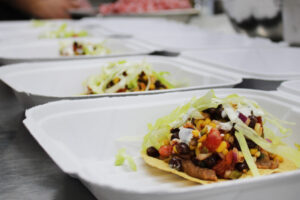 vegetarian tostadas in take out boxes topped with lettuce and sour cream