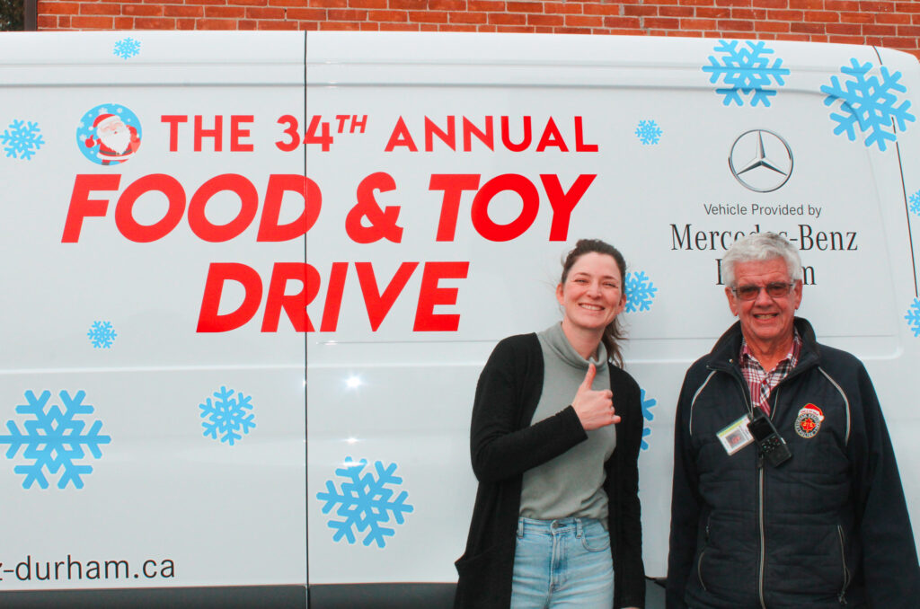 Beth accepts a donation from DRPS' 34th annual Food and Toy Drive with a thumbs up!