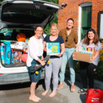 Johanne, Eliza, and Beth pose with a donation of tangible goods for transitional housing from North House