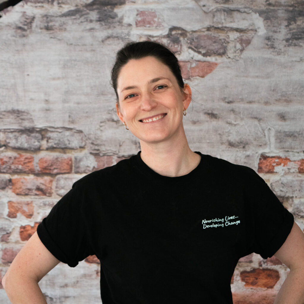 Headshot of Beth, our Food Services Manager, in front of a brick wall.