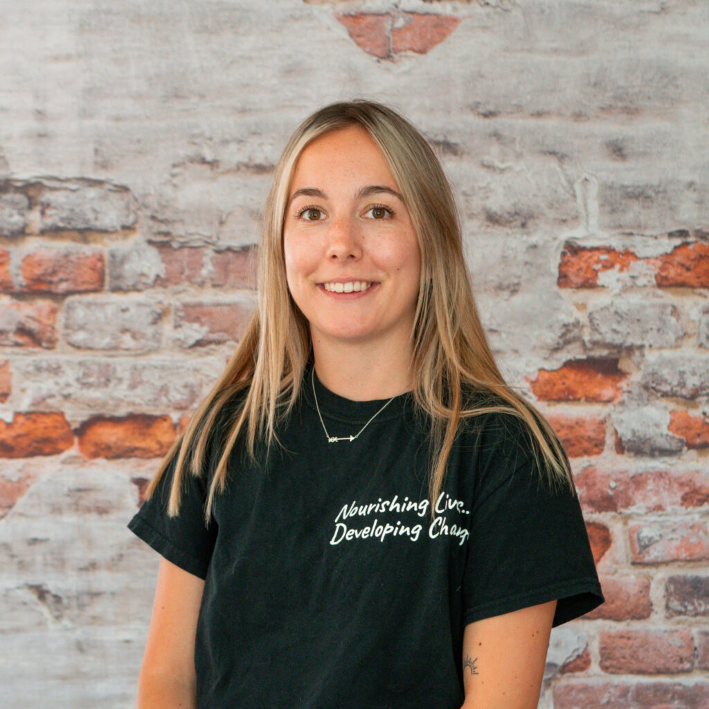 Headshot of Karley, our Food Literacy Coordinator, in front of a brick wall.