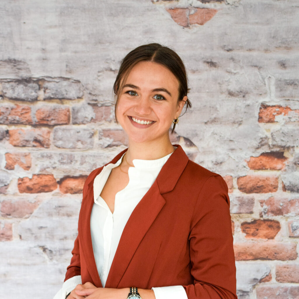 Headshot of Katerina, our Fundraising and Advocacy Coordinator, in front of a brick wall.