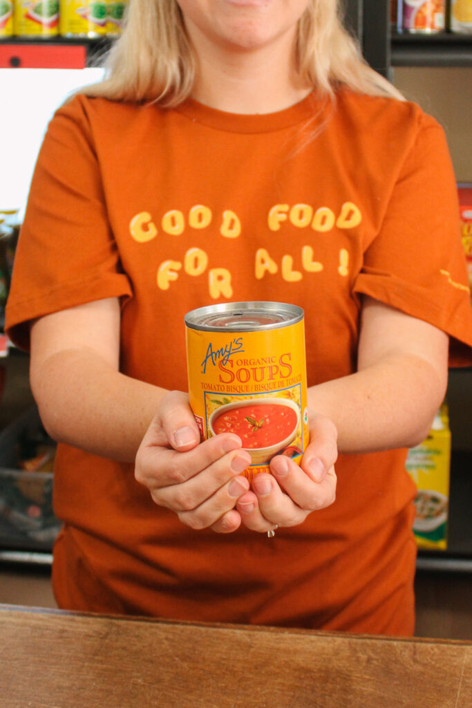 Individual holding a soup can of tomato soup as main subject