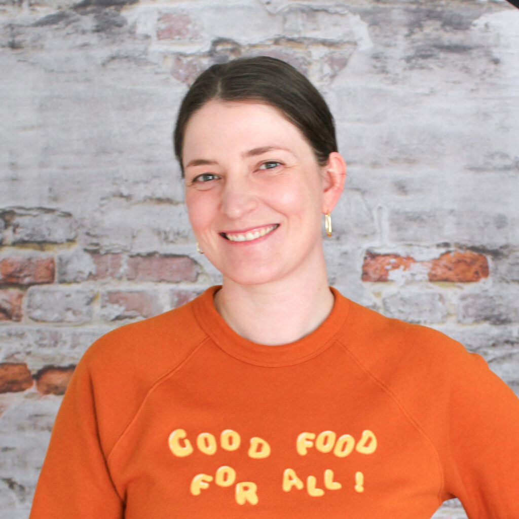 Headshot of Beth, staff member, in front of a brick wall.