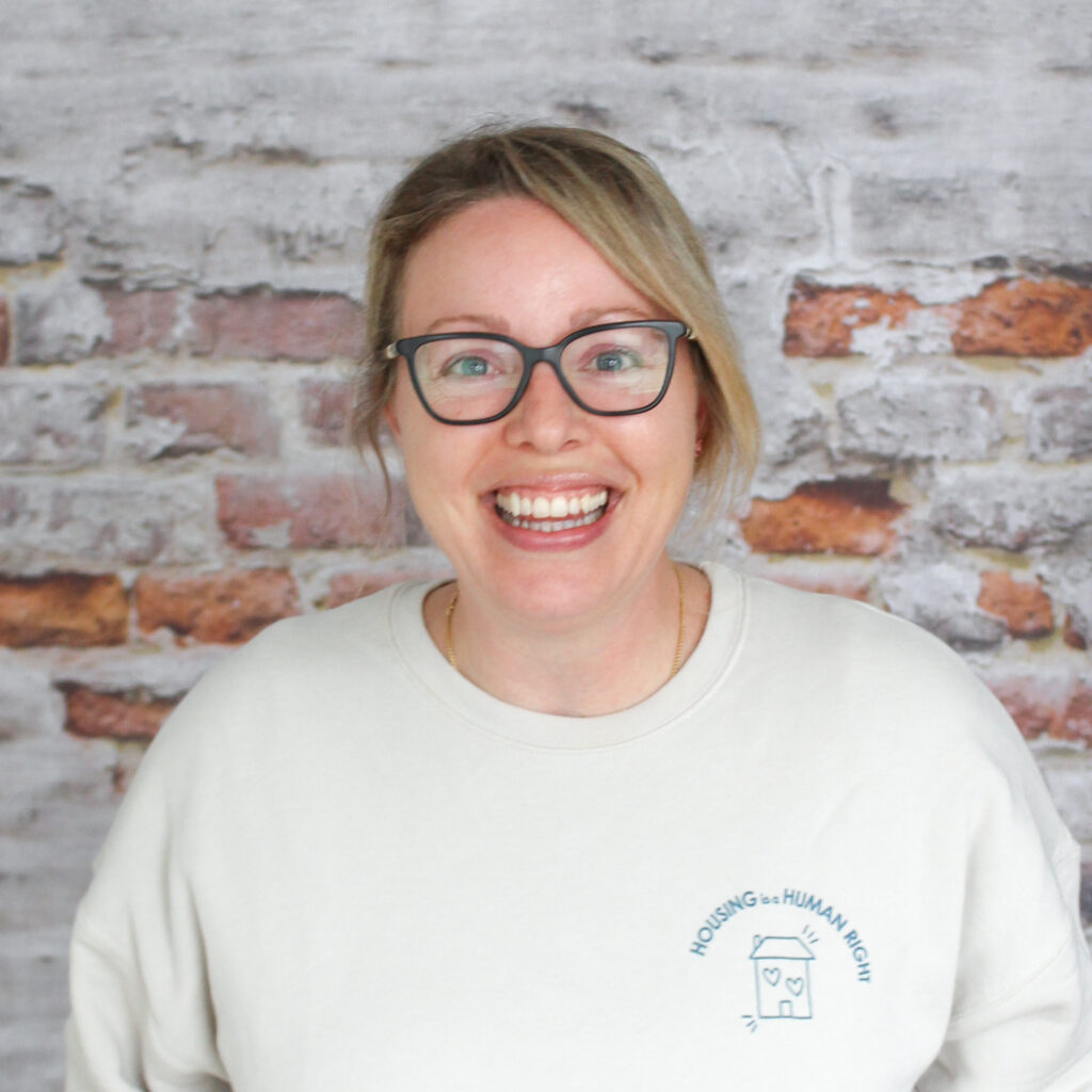 Headshot of Lisa, our Food Bank Coordinator, in front of a brick wall.