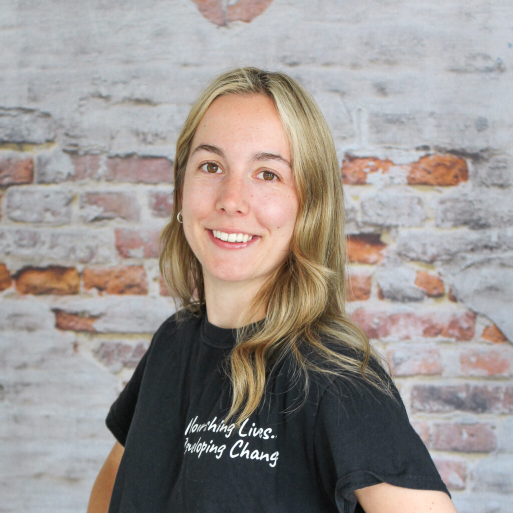 Headshot of Karley, our Food Literacy Coordinator, in front of a brick wall.