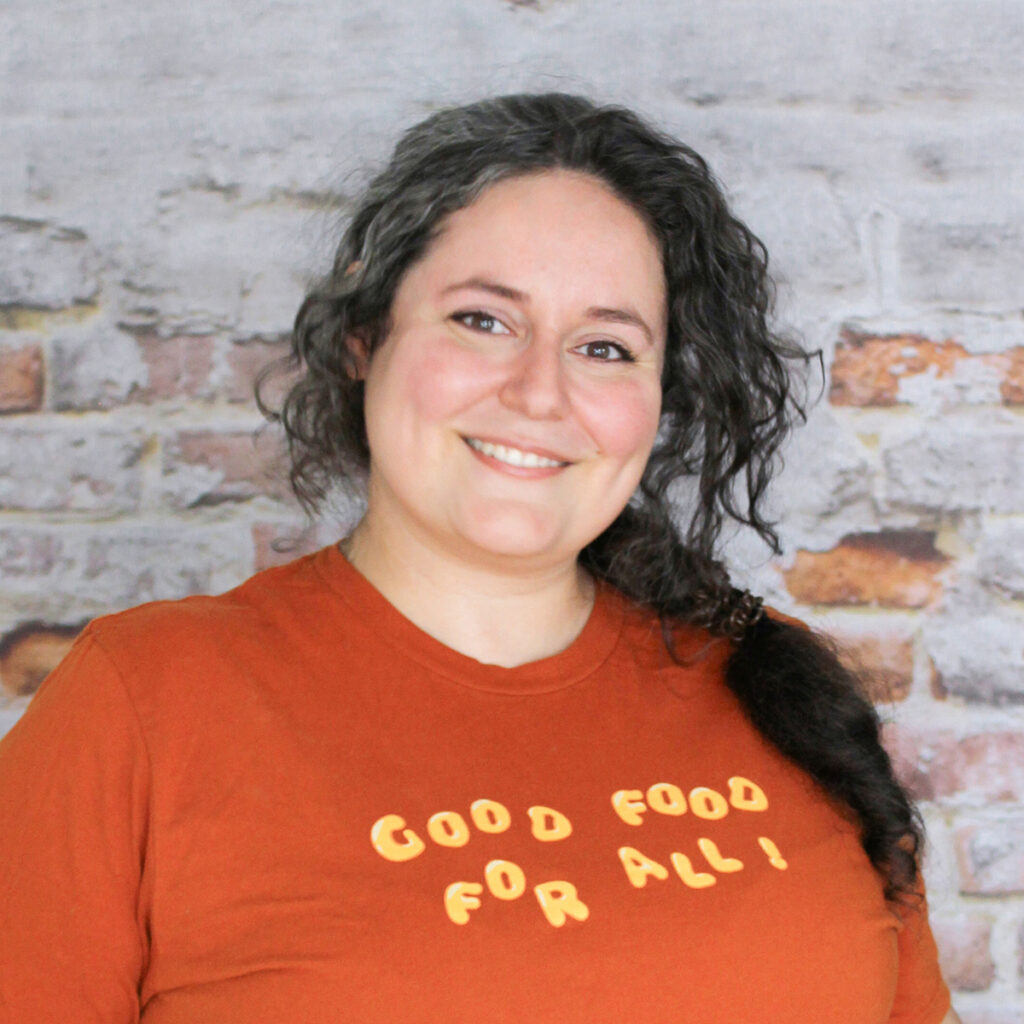 Headshot of Kate, staff member, in front of a brick wall.