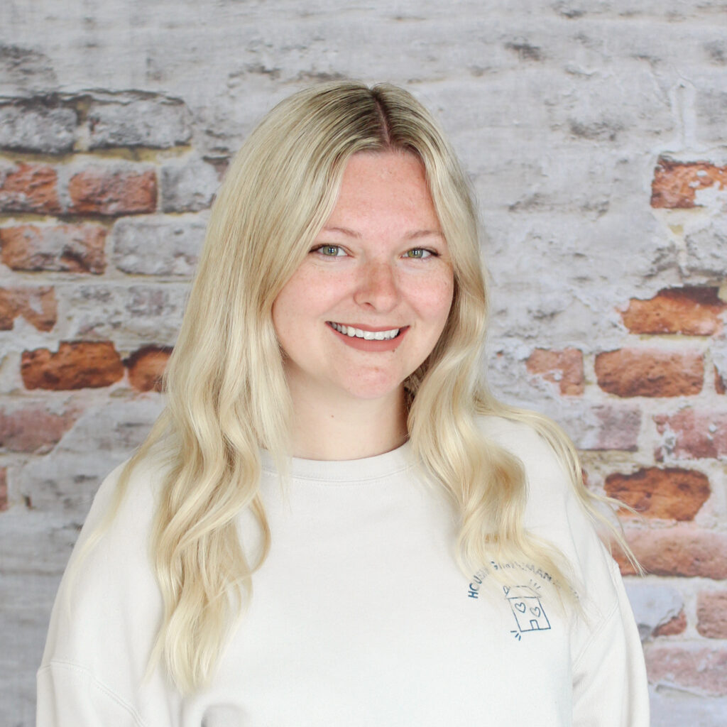 Headshot of Mackenzie, staff member, in front of a brick wall.