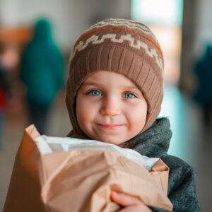 Little boy in winter hat holding a food bank order