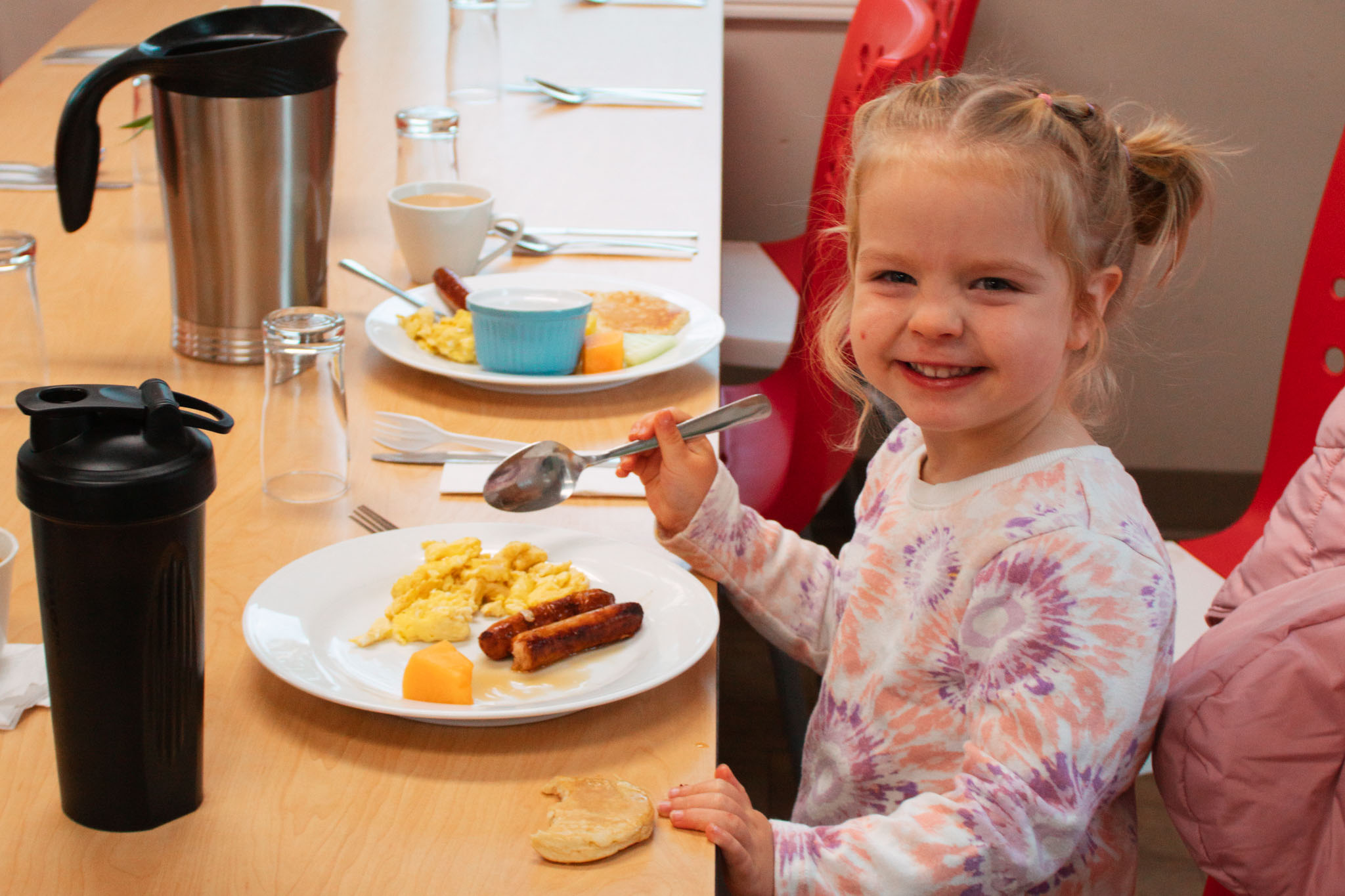 A little girl eats breakfast at Community Breakfast