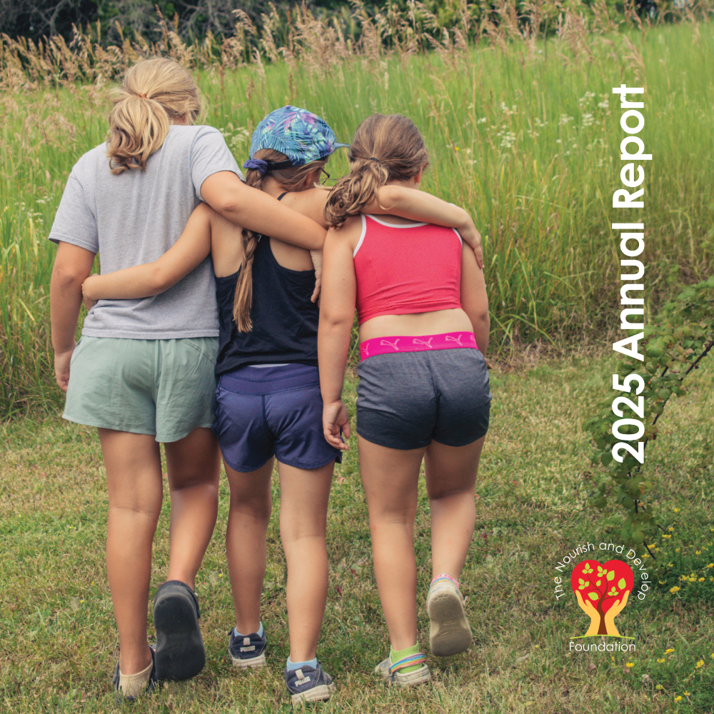 3 girls walk arm and arm through a garden in our Annual Report Cover for 2025