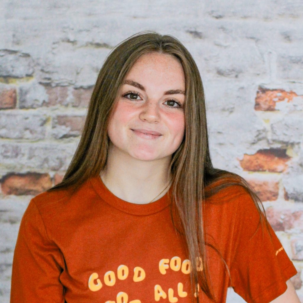 Headshot of Alicia, staff member, in front of a brick wall.