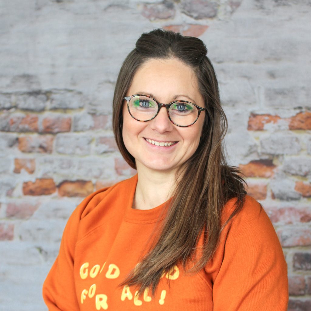 Portrait of Kristin in front of a grey brick wall