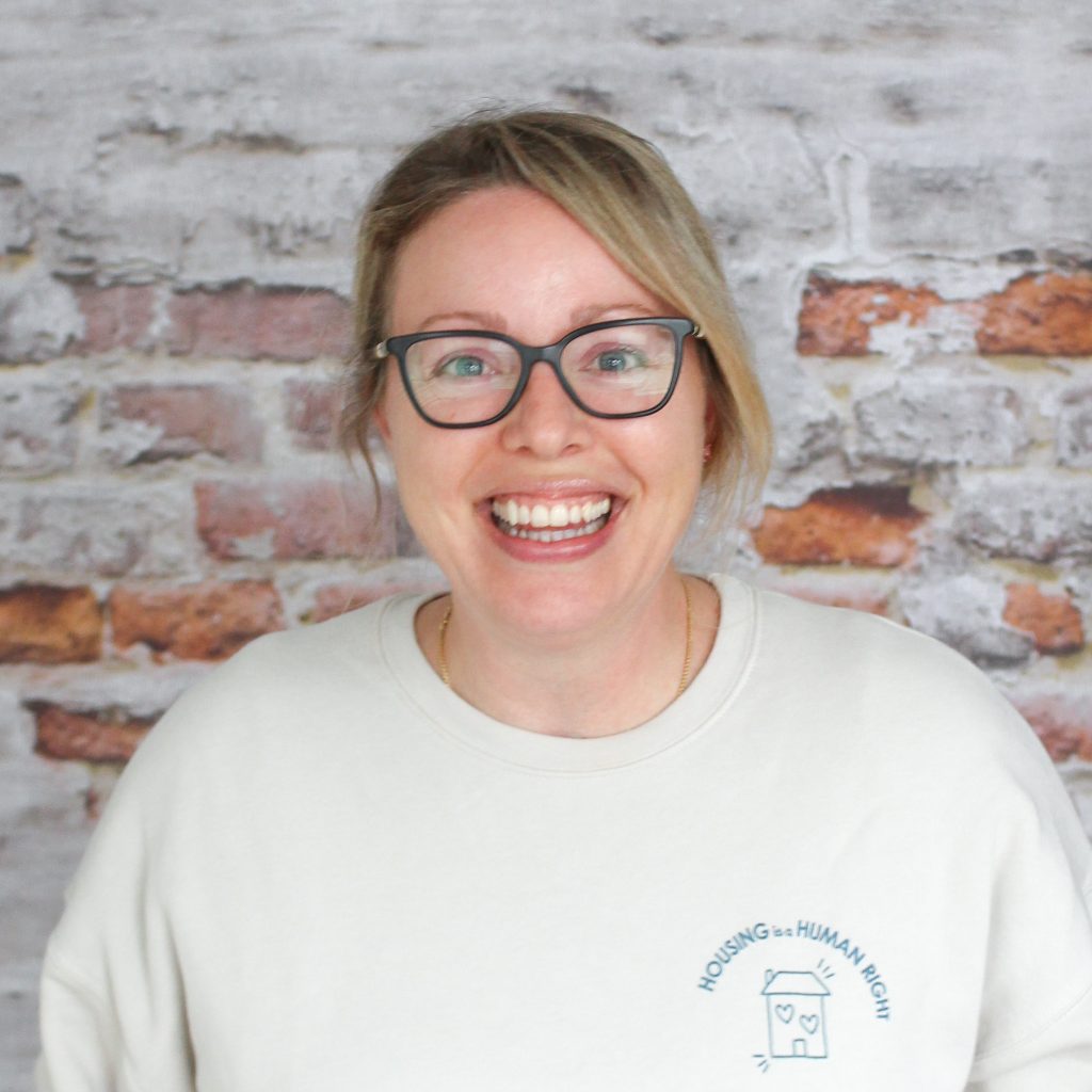Headshot of Lisa, our Food Bank Coordinator, in front of a brick wall.